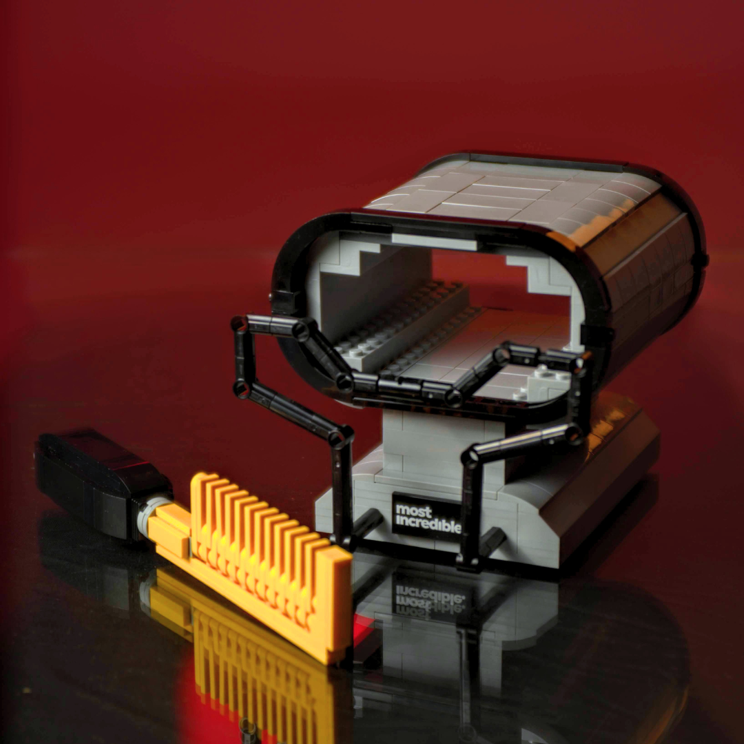 Toy microscope and eyepiece on a reflective surface with a red background made of Lego