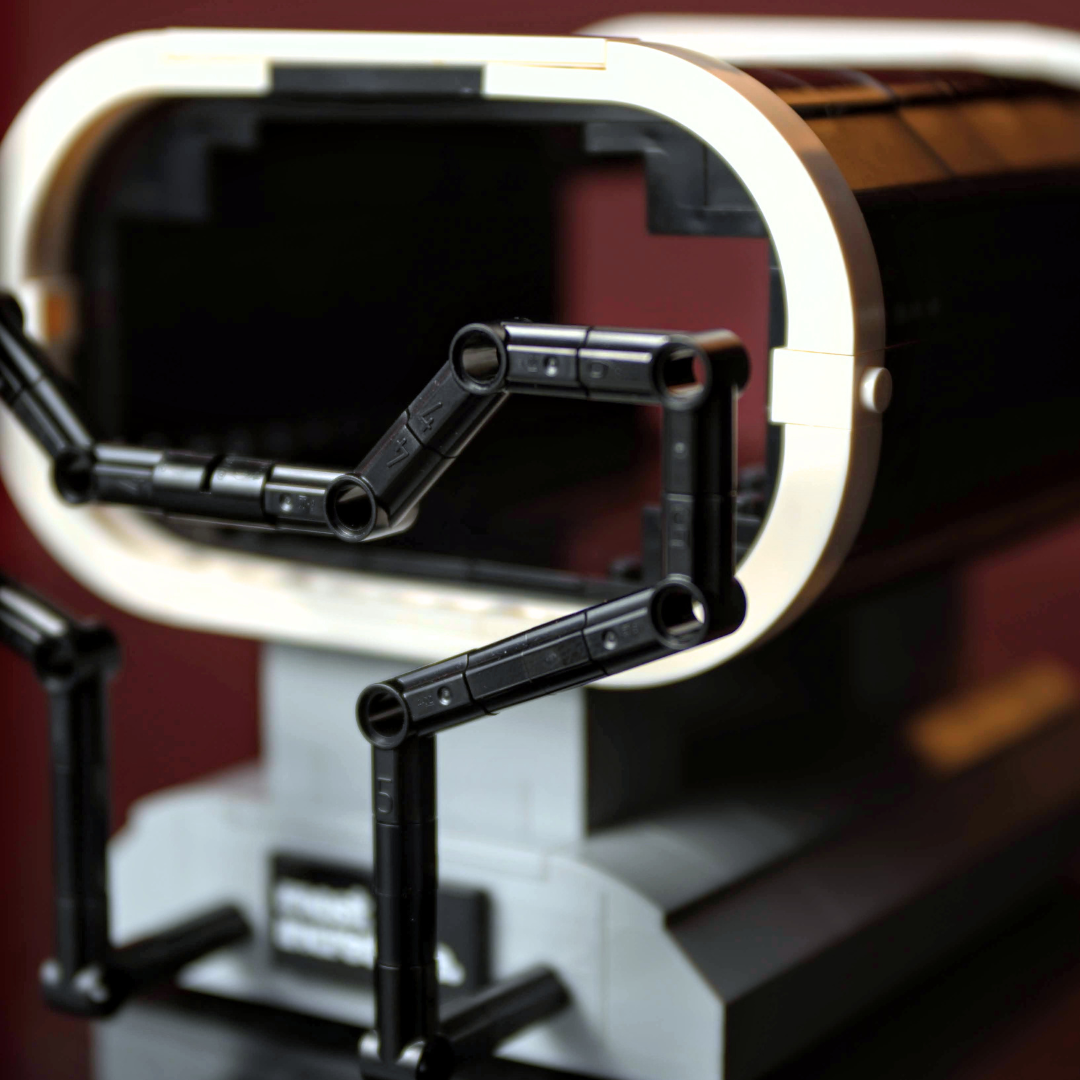 Close-up of a mechanical device with a metallic ring and black metal arms on a blurred background made of Lego