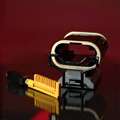 Toy-like device with yellow component and black and white structure on a reflective surface with red background